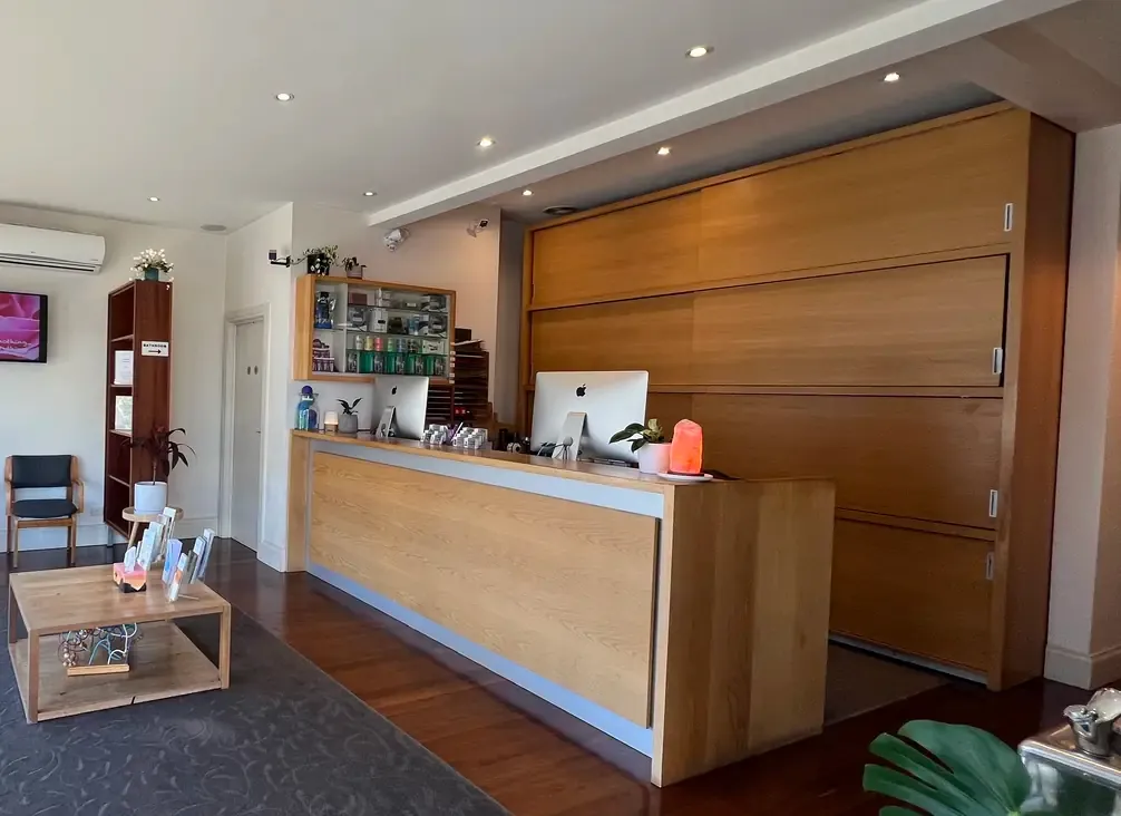 The clinic's reception desk, with a stocked product shelf behind it and a small waiting area beside it