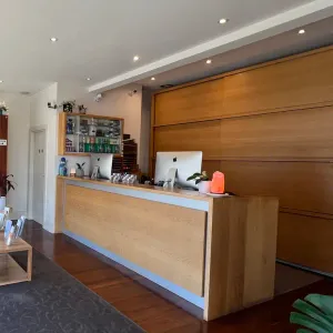 The clinic's reception desk, with a stocked product shelf behind it and a small waiting area beside it