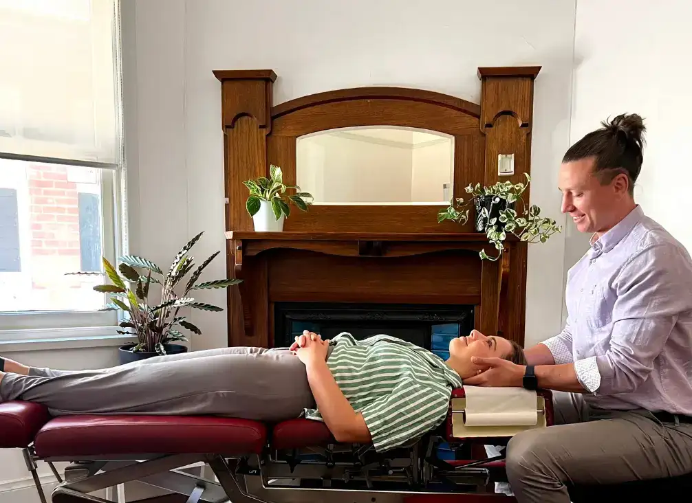 Dr Kenneth Taylor assessing a patient's neck while they lie on a treatment table