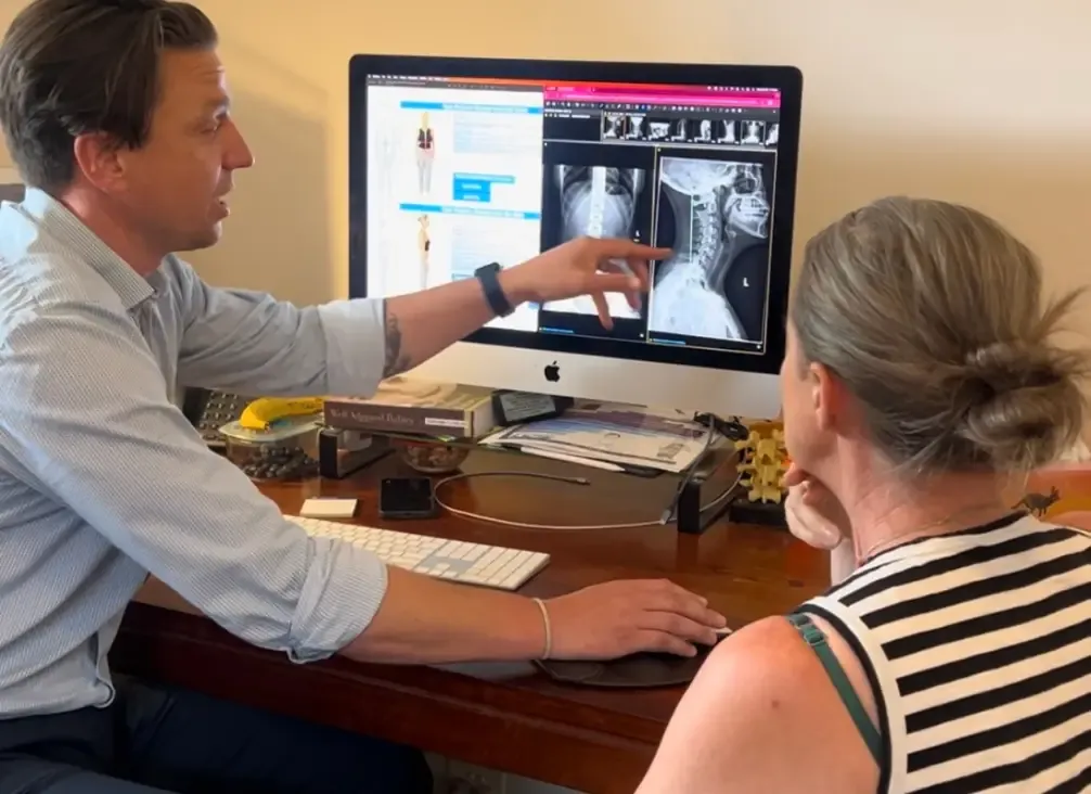 A chiropractor talking a patient through their X-rays