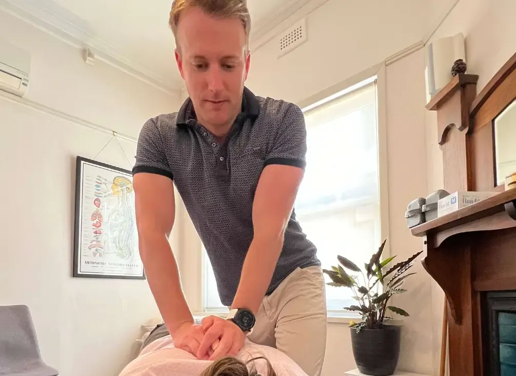 A chiropractor working through a patient's shoulder and upper back