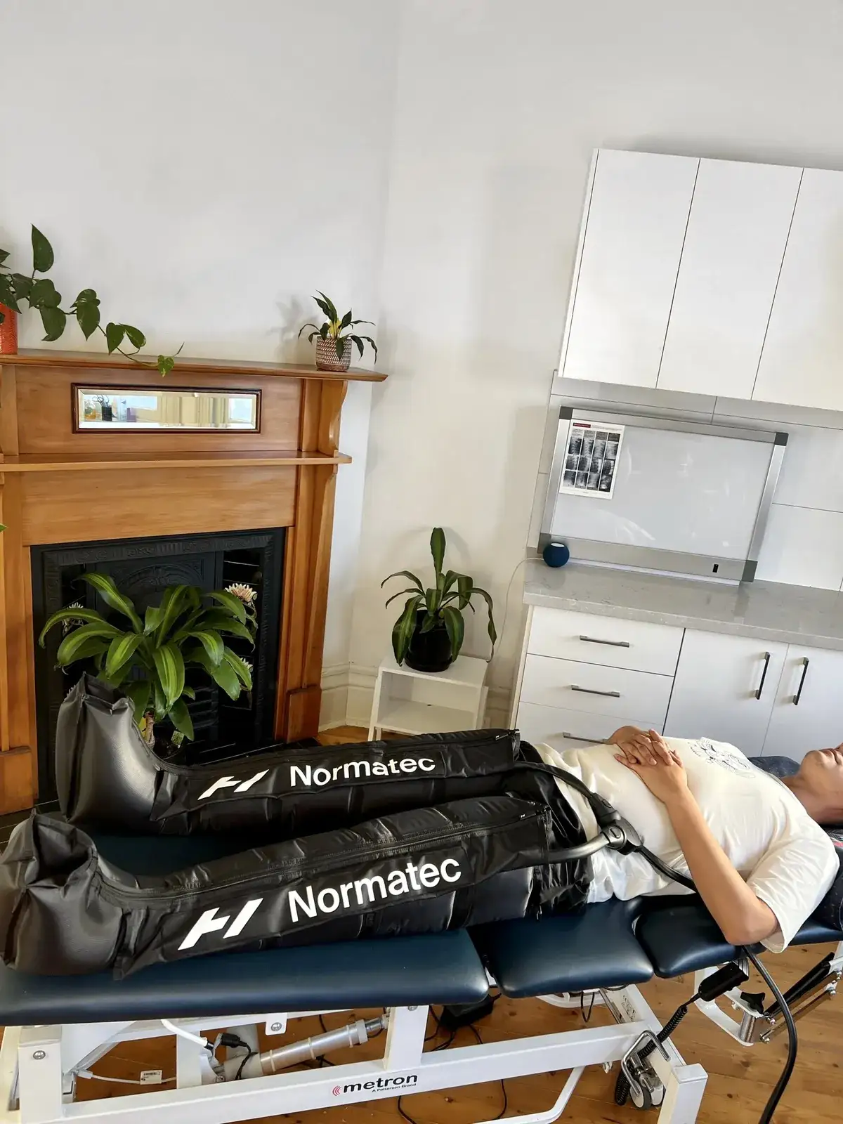 A patient resting on a treatment table with inflatable compression boots on both legs