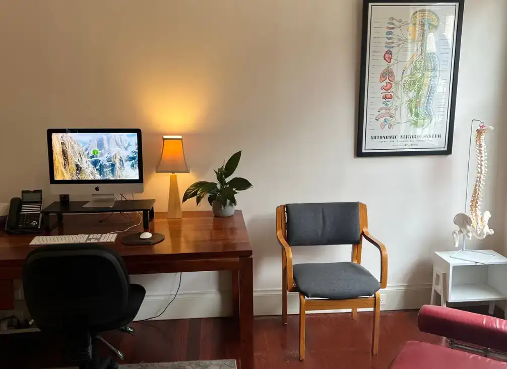 A chiropractic consultation room with a treatment table and desk