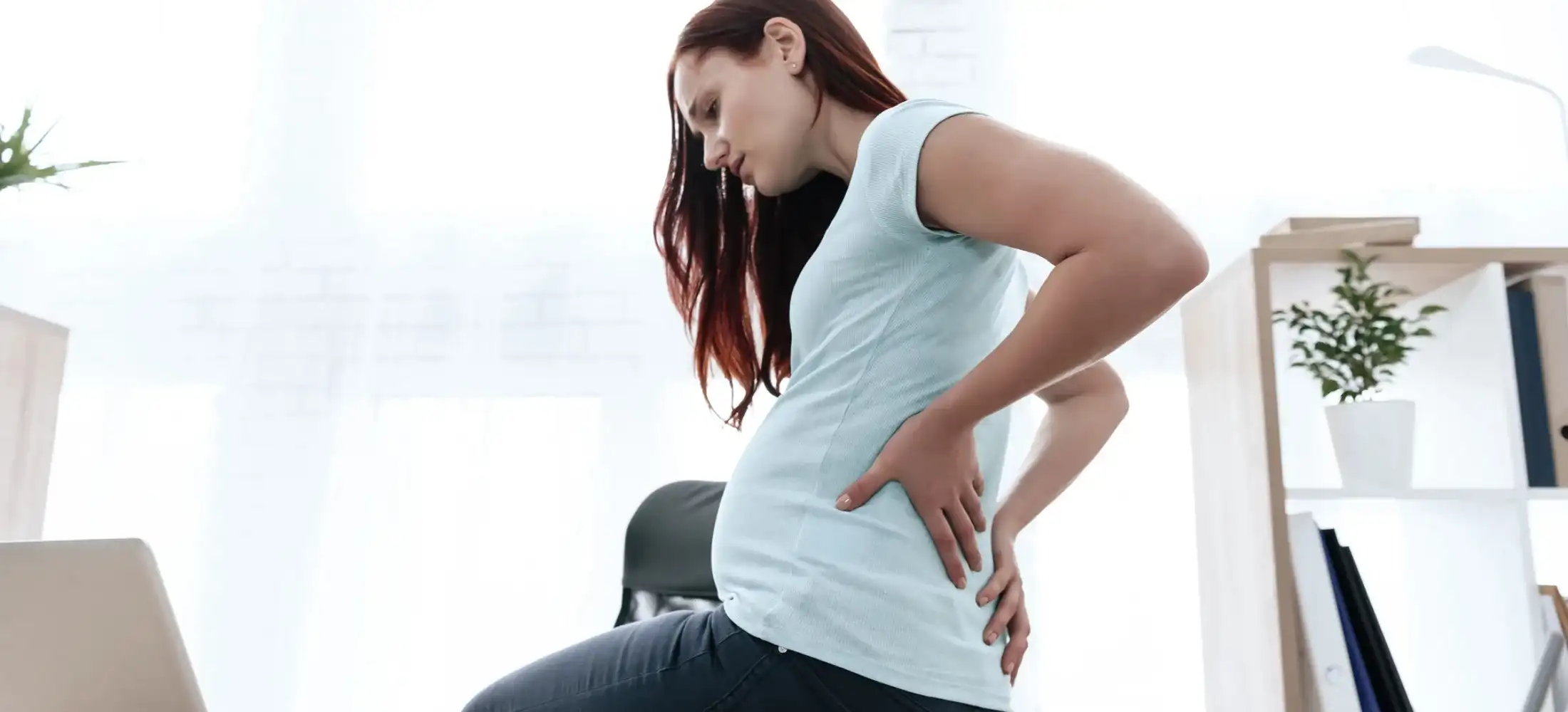 A pregnant woman supporting her lower back with one hand