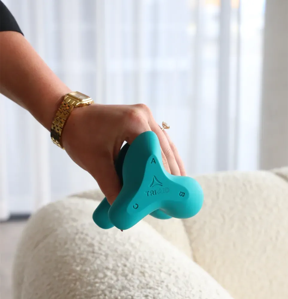 A hand pressing the device into the arm of a couch, showing how it fits the palm