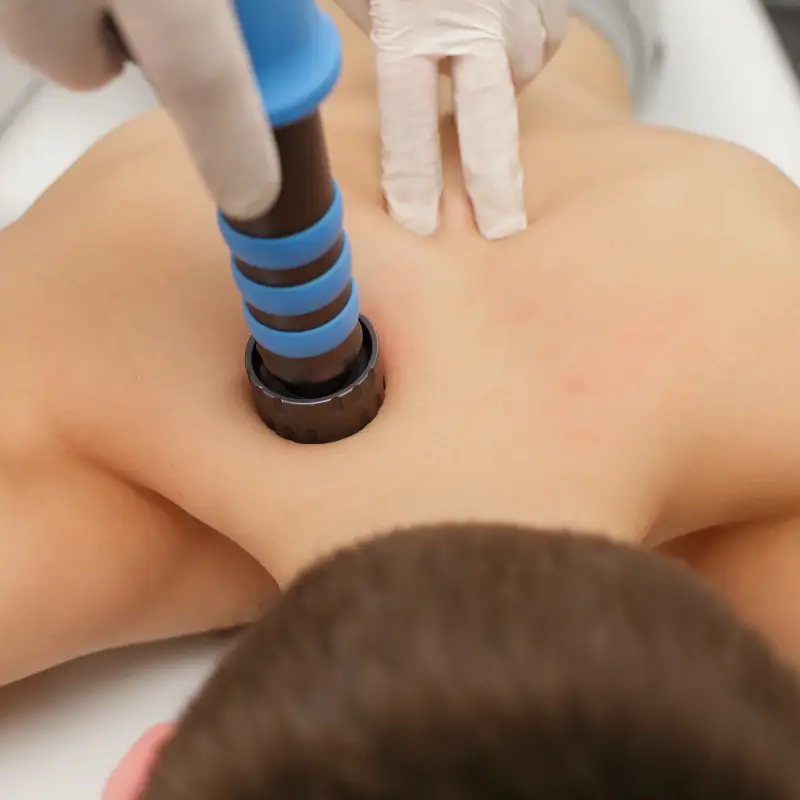 Chiropractor Melbourne applying shockwave therapy to upper back for pain relief