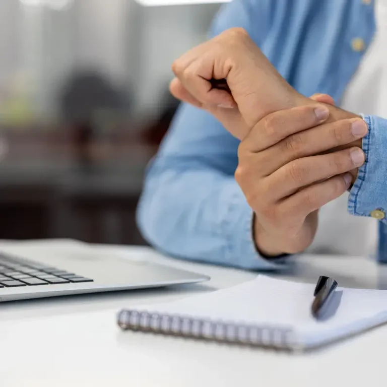 Person holding their wrist in pain while working at a desk